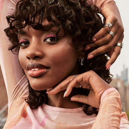 Woman with pink makeup and a blurred cityscape background