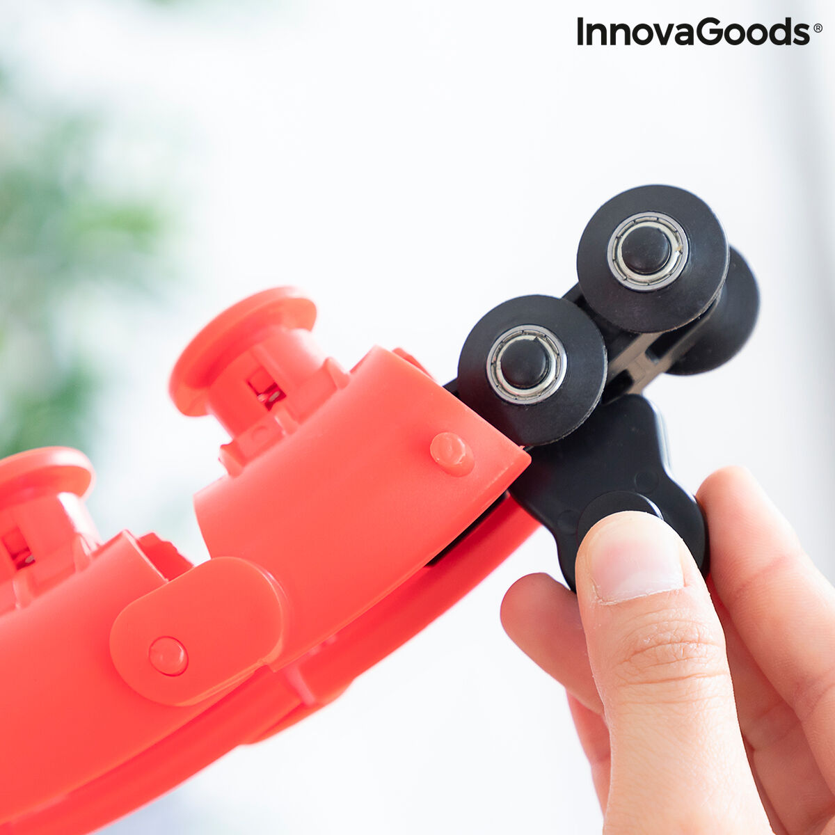 Red and black cable stripper being used with a blurred green plant background
