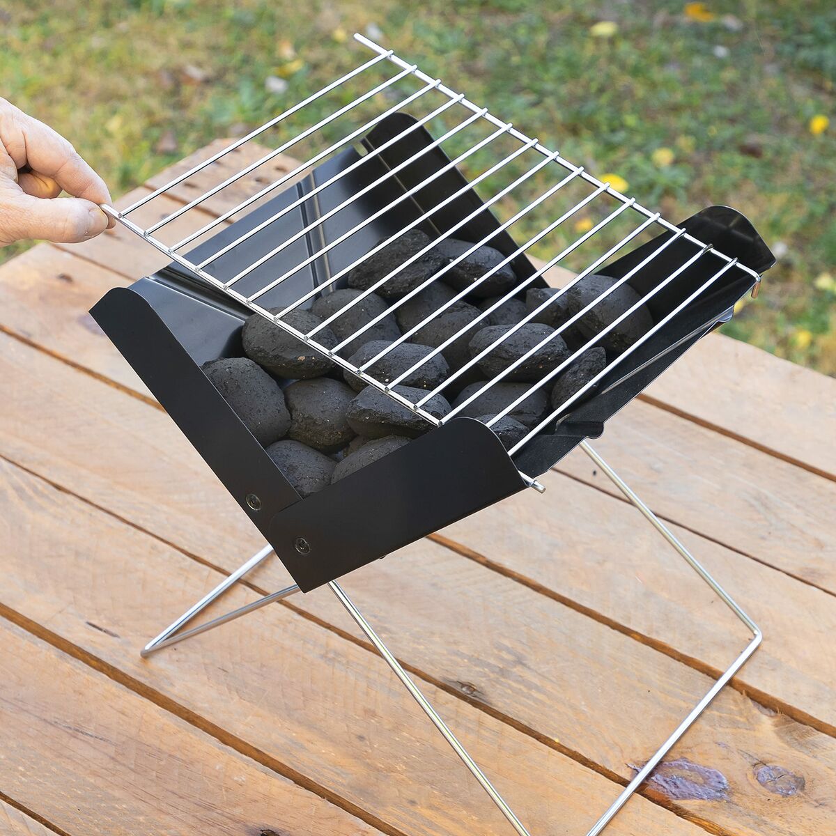 Portable grill with charcoal on a wooden surface outdoors
