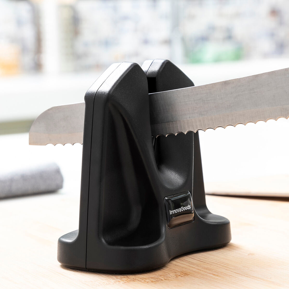 Knife sharpener with a serrated knife on a wooden surface