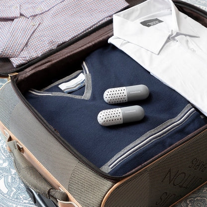 Open suitcase with folded clothes and gray travel pillows on a textured surface