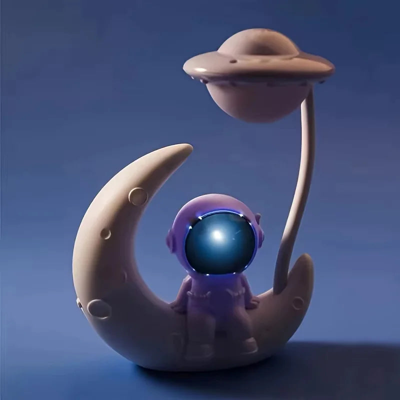 Toy figure of an astronaut on a moon with a UFO above, against a blue background
