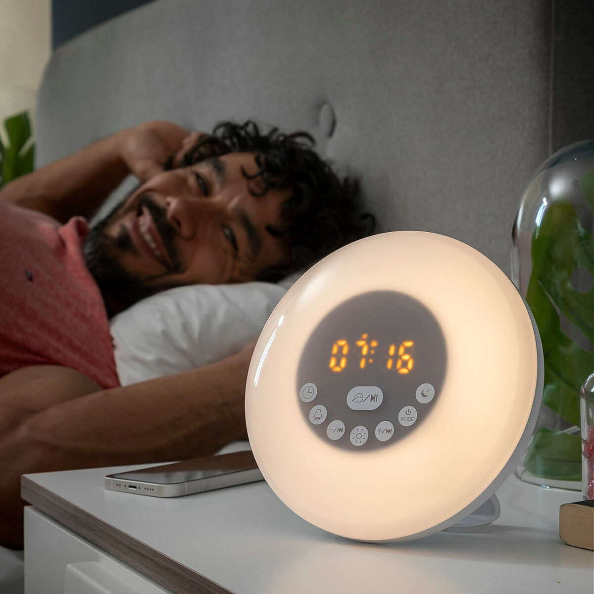 Person lying in bed with a digital clock on a nightstand